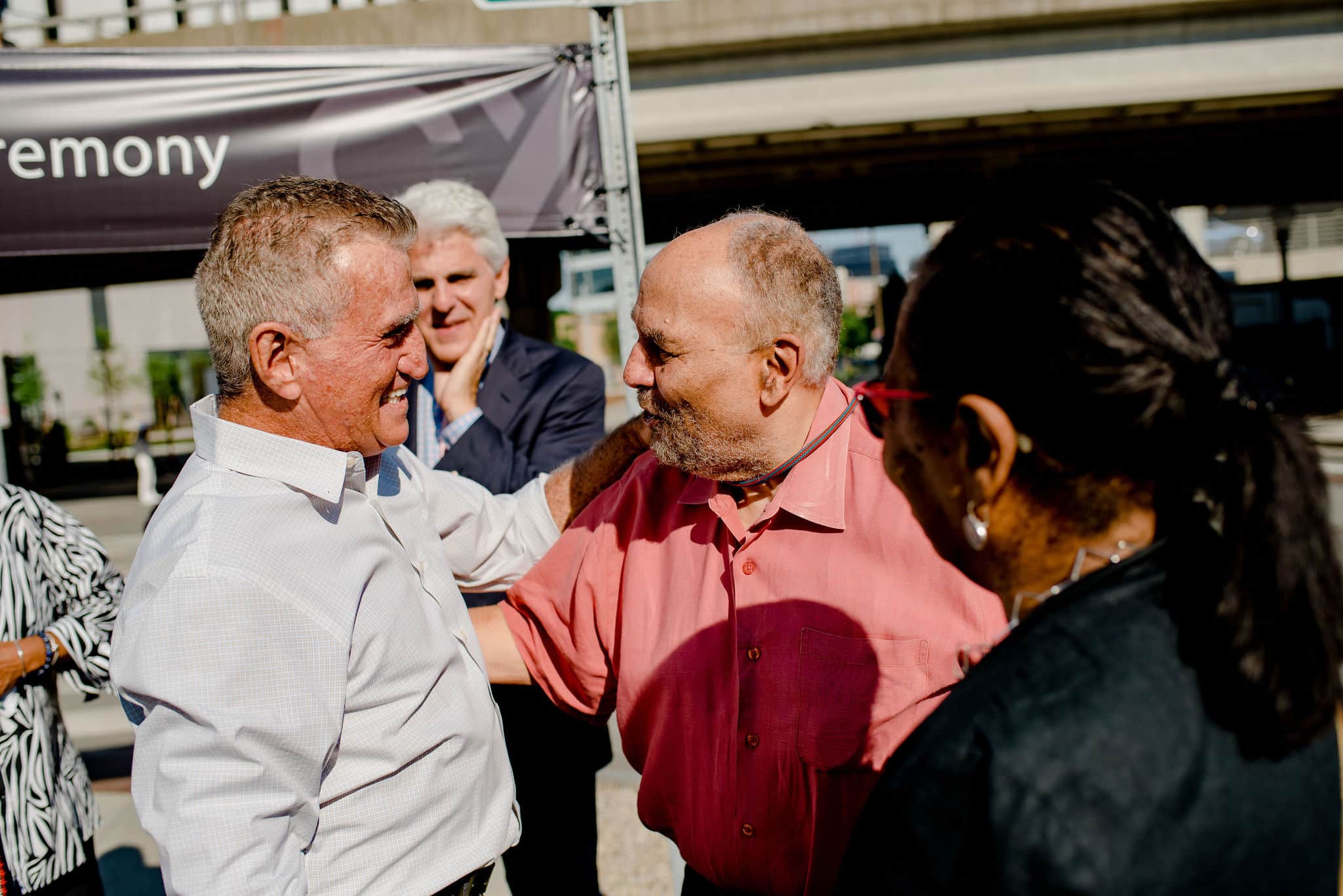 Two men greet warmly during Jacobs and Morgan unveiling ceremony surrounded by smiling attendees