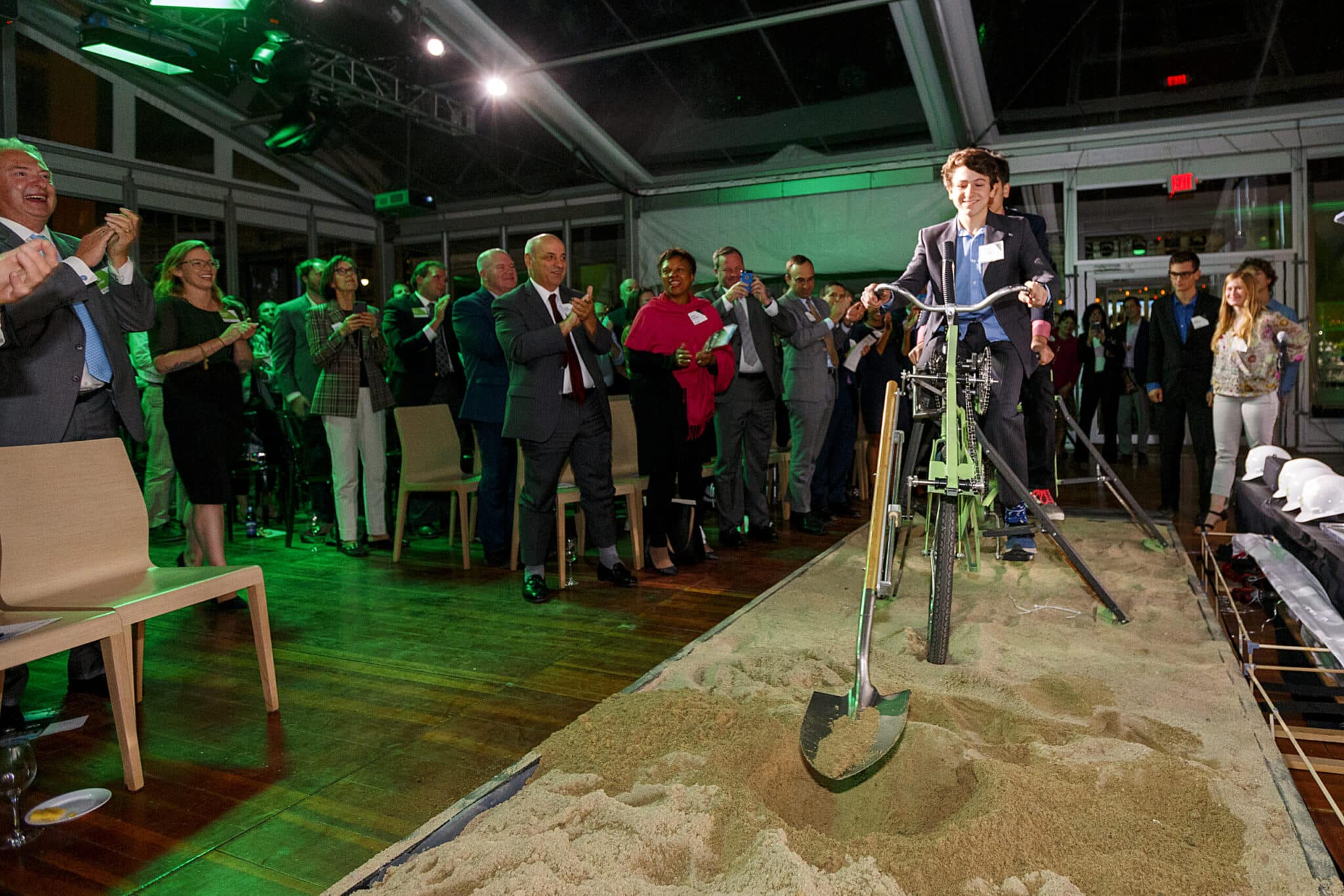 Man on stationary bicycle breaks ceremonial sand while guests cheer during CX event