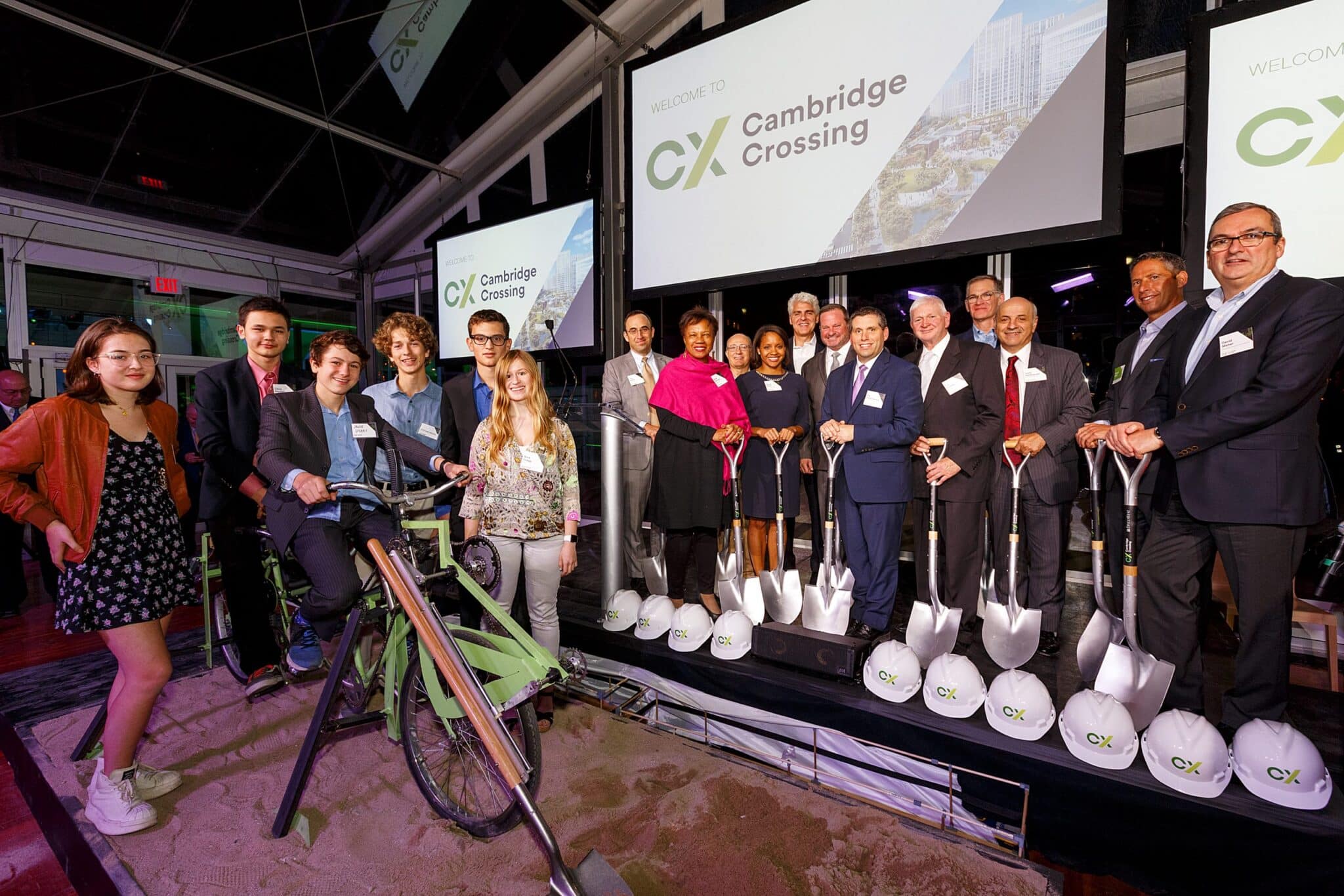 Group photo on indoor sandpit with ceremonial tools and Cambridge Crossing branding behind