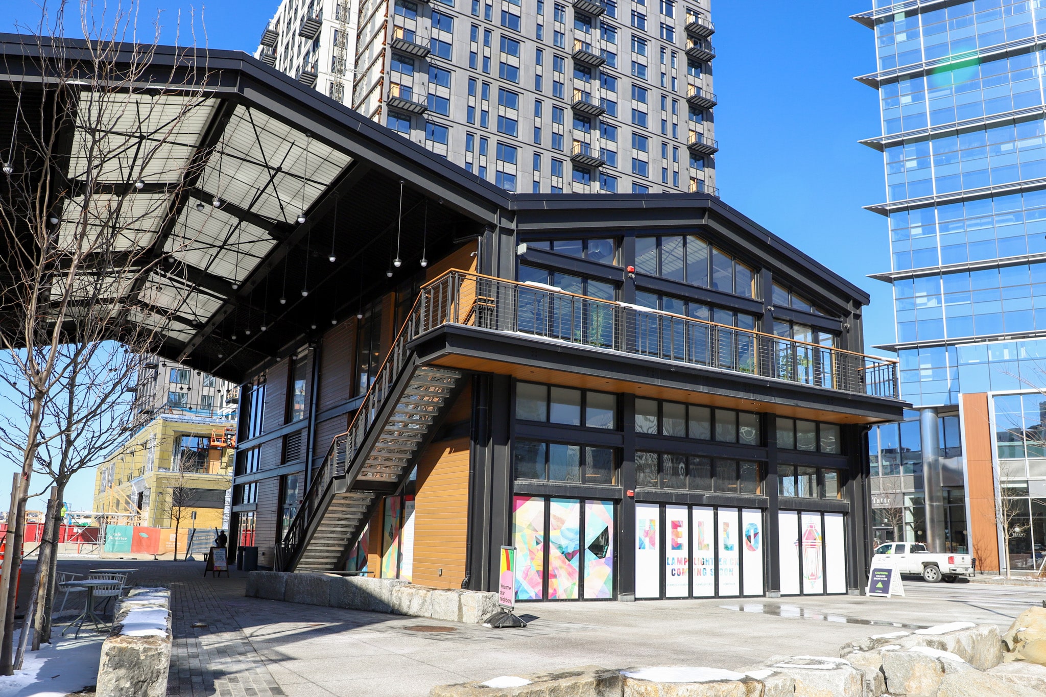 Modern building with exposed staircase and glass windows situated among tall high-rise structures