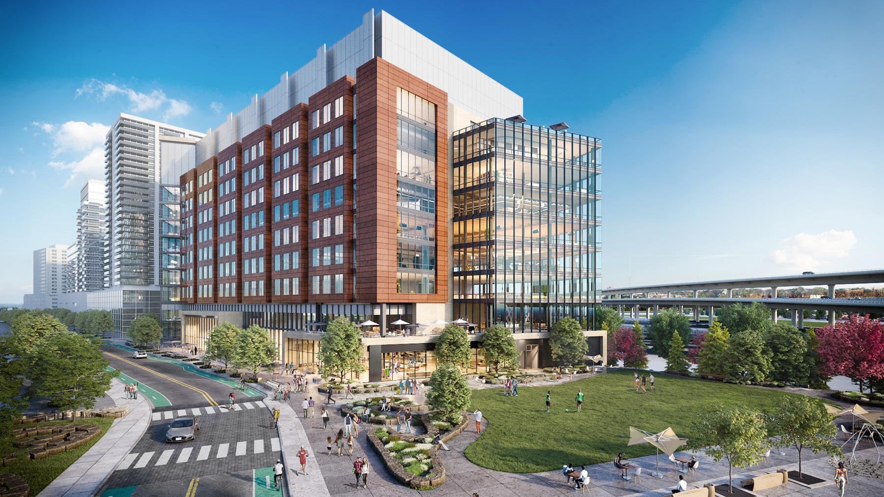 Large modern mixed-use building with glass facade and adjacent landscaped public green space