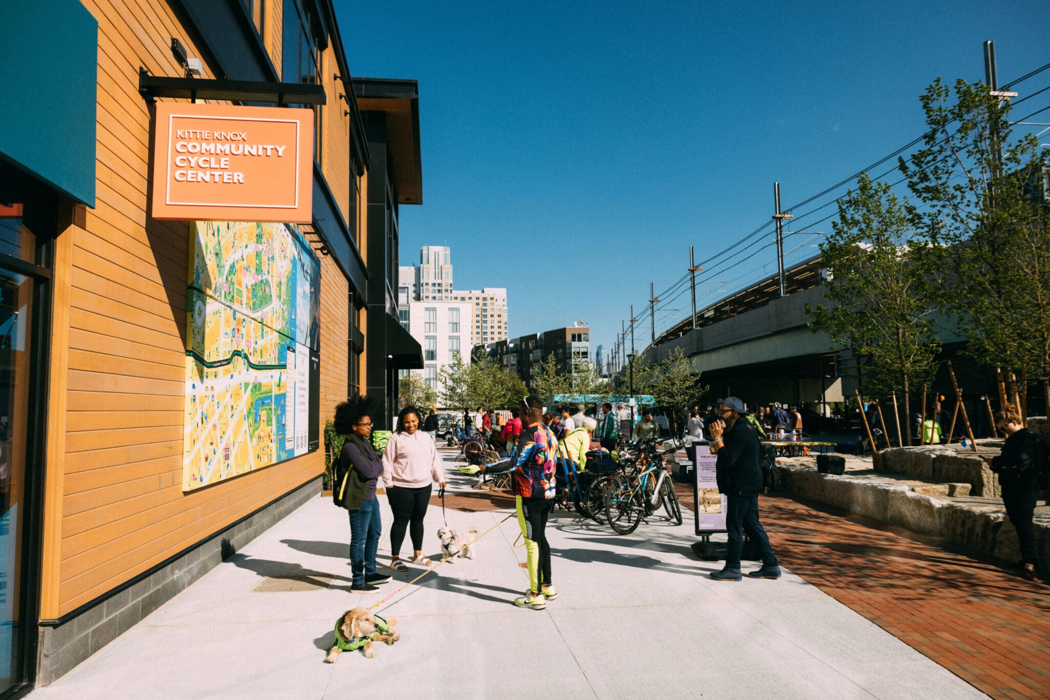 People gather with dogs and bicycles outside Kittie Knox Community Cycle Center in Cambridge