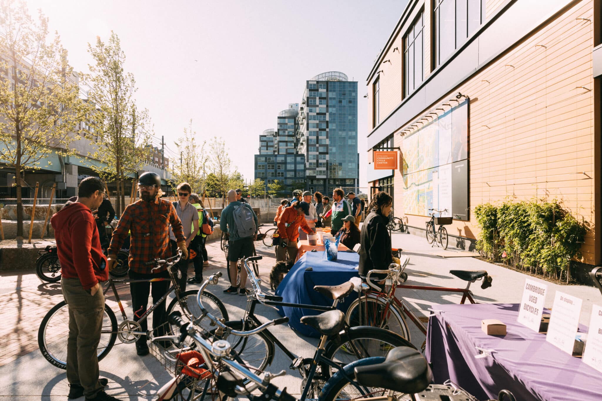 Cyclists network and explore vendor tables during sunny event outside Cambridge facility