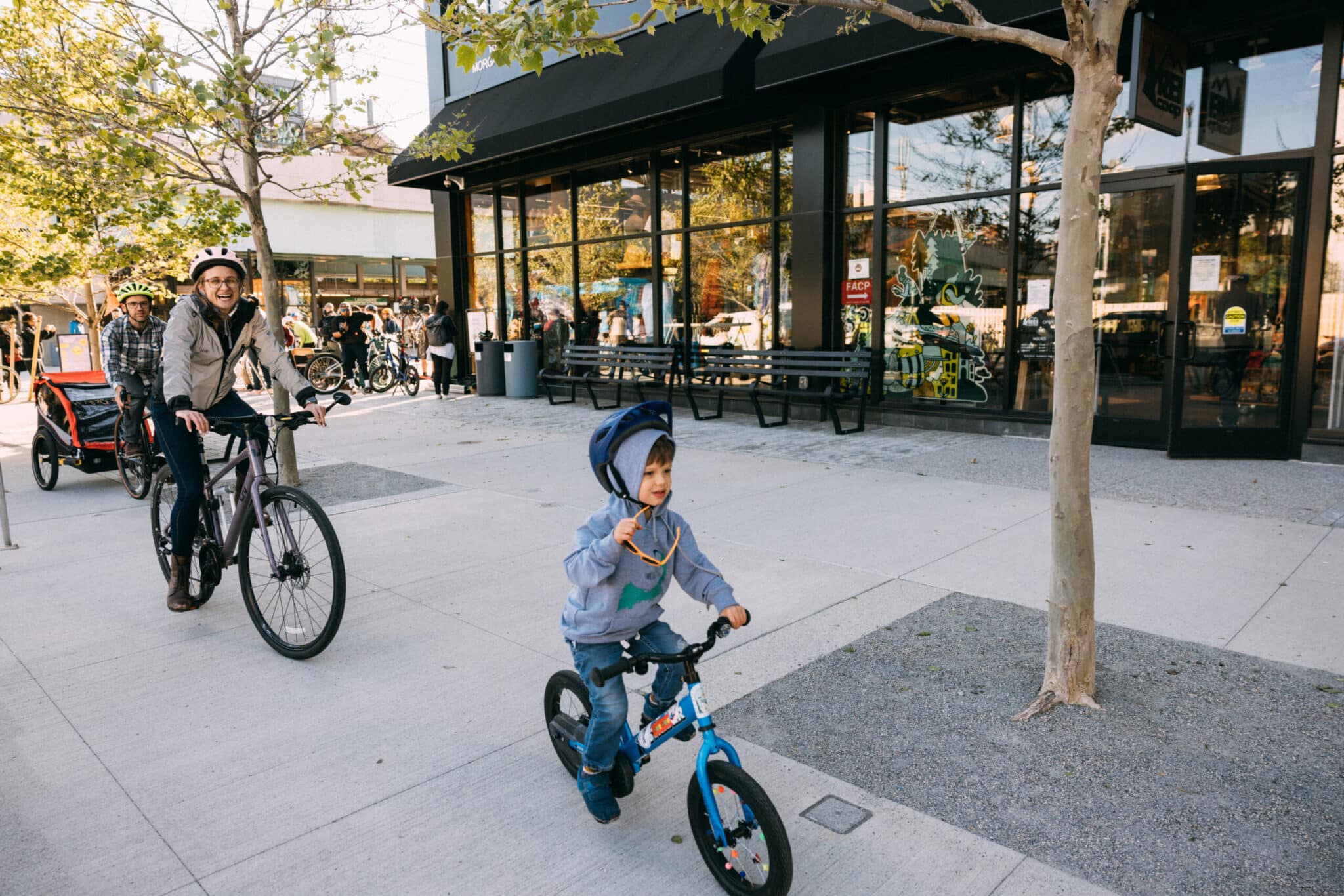 Smiling child rides small bicycle with adults biking behind during fun group cycling activity