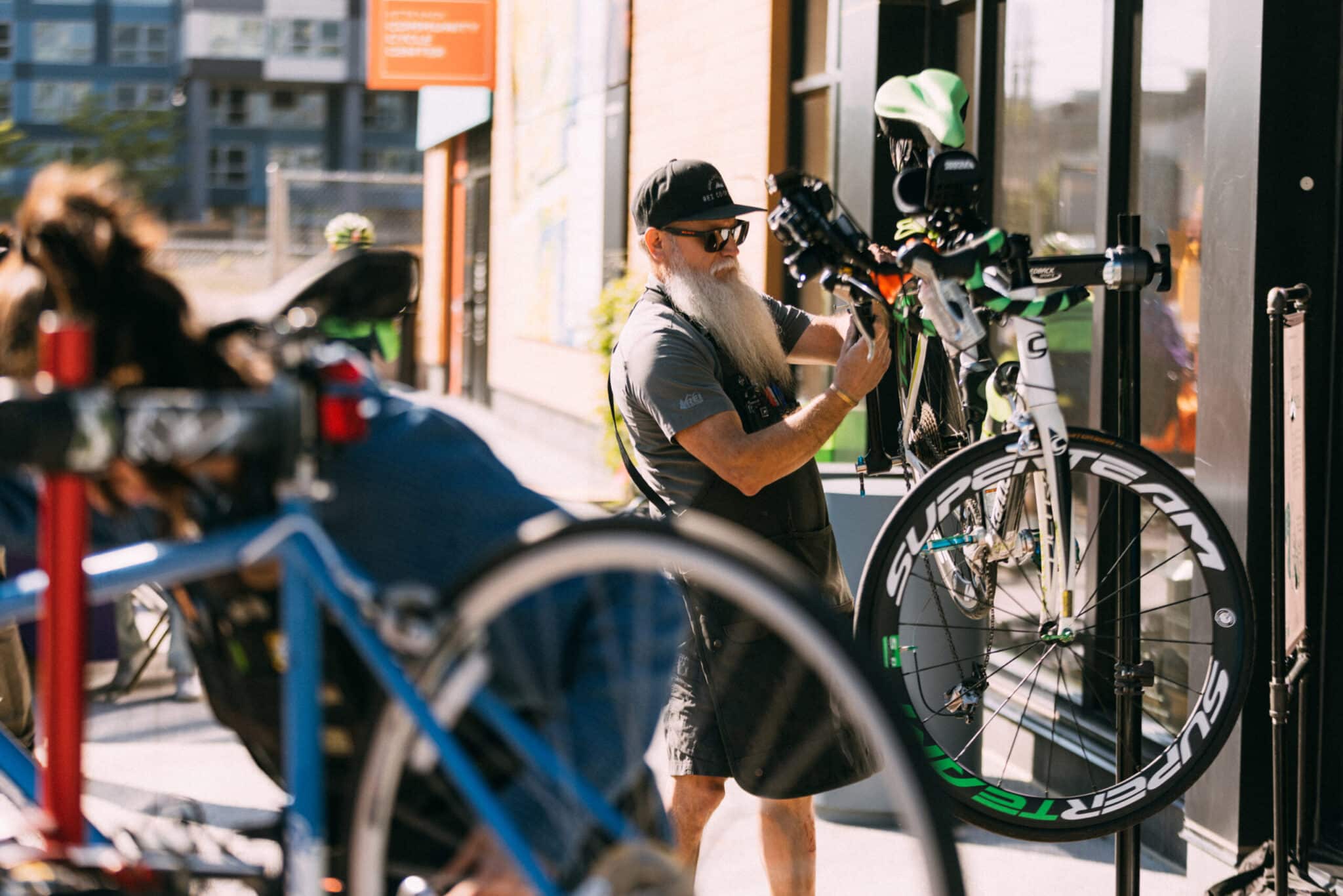 Bearded technician works on high-performance road bike during outdoor maintenance event