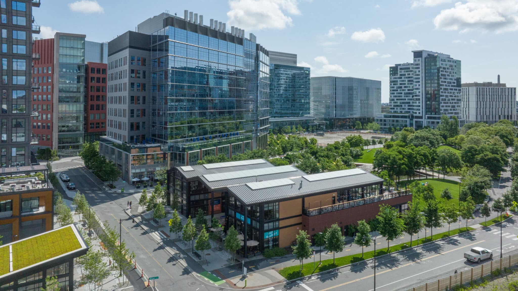Aerial view of modern glass buildings surrounded by greenery at Cambridge Crossing development