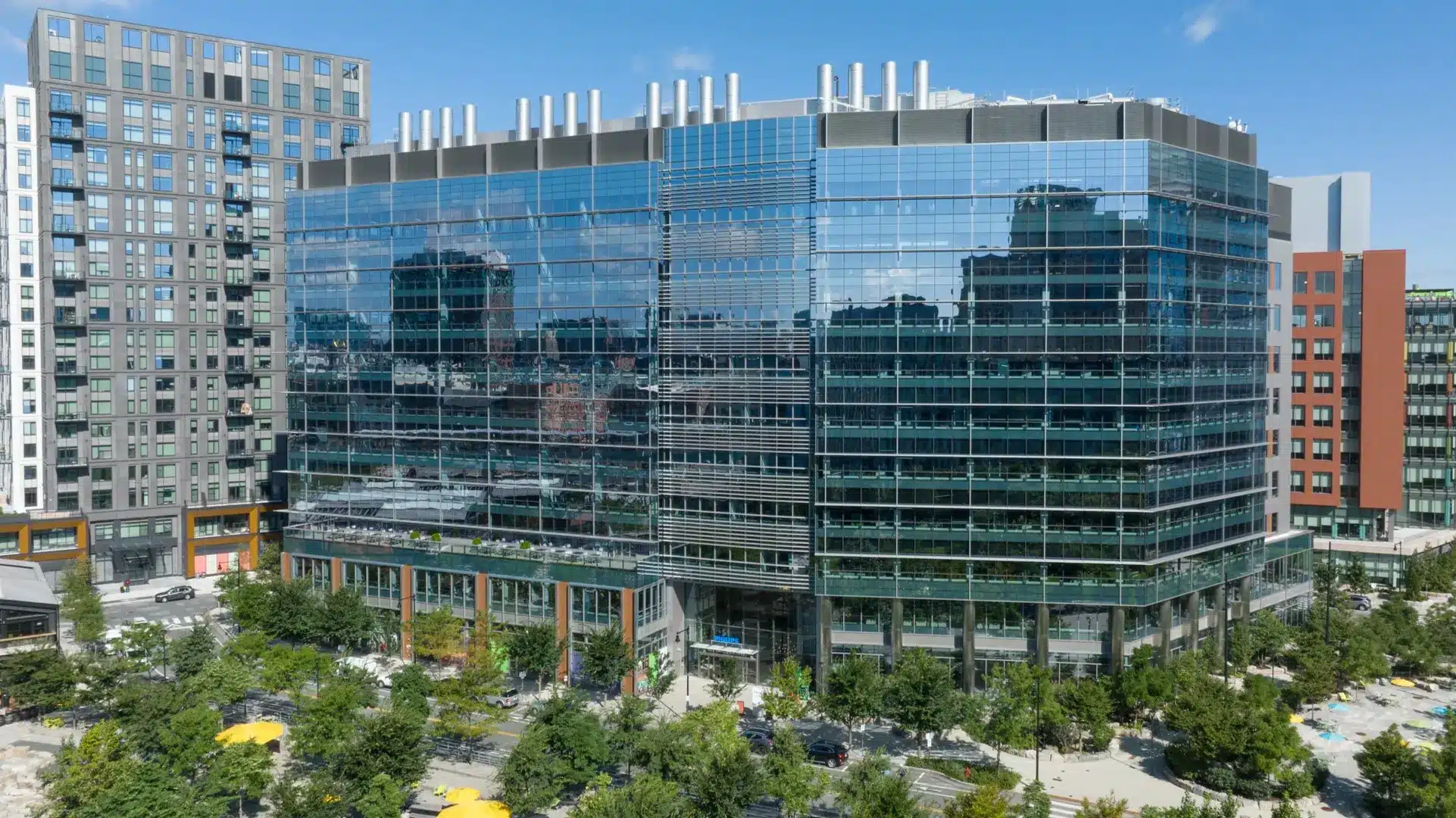 Large reflective glass office tower mirrors surrounding cityscape and residential buildings