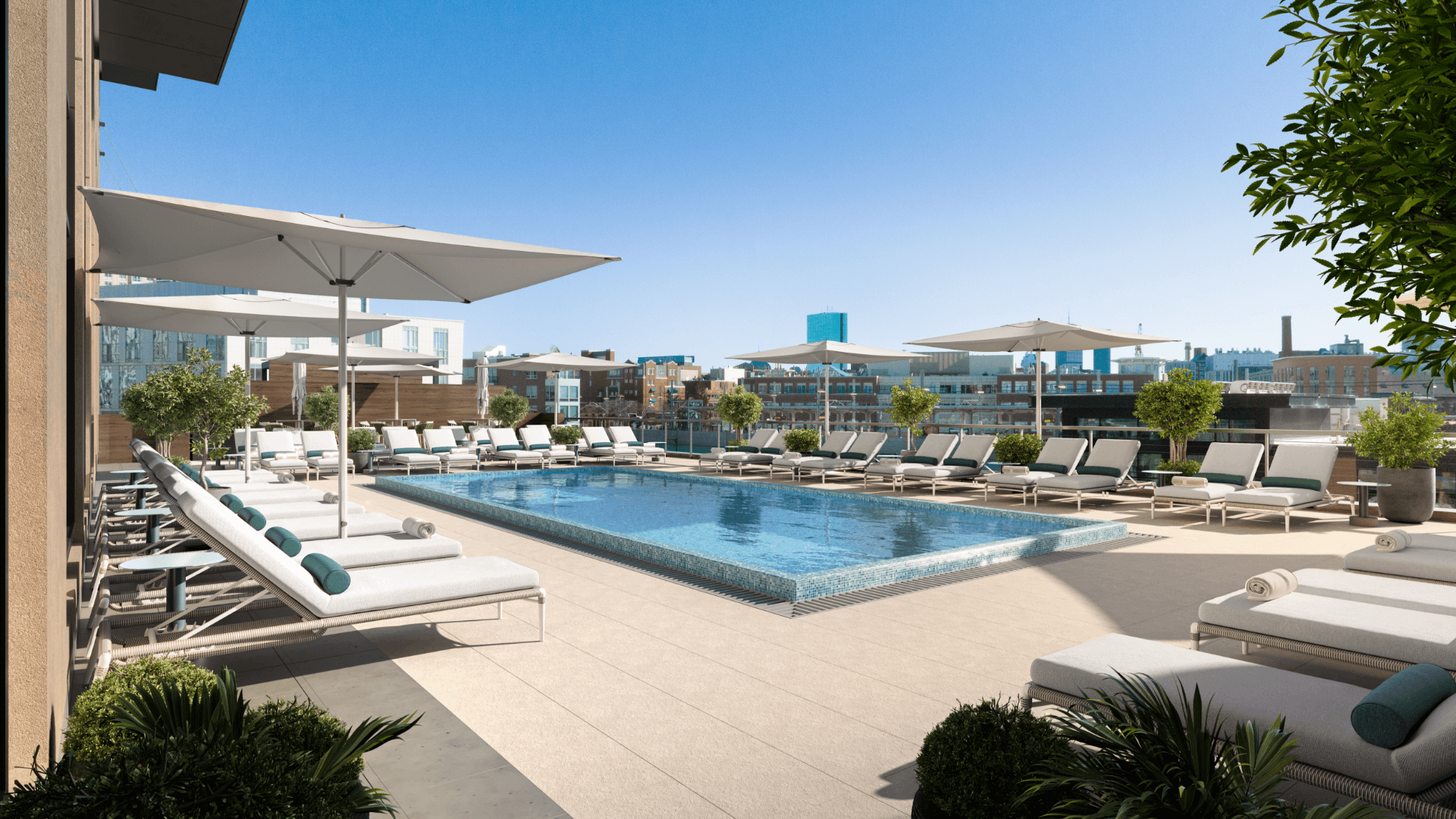 Rooftop pool deck with lounge chairs, umbrellas, and skyline views under clear blue sky
