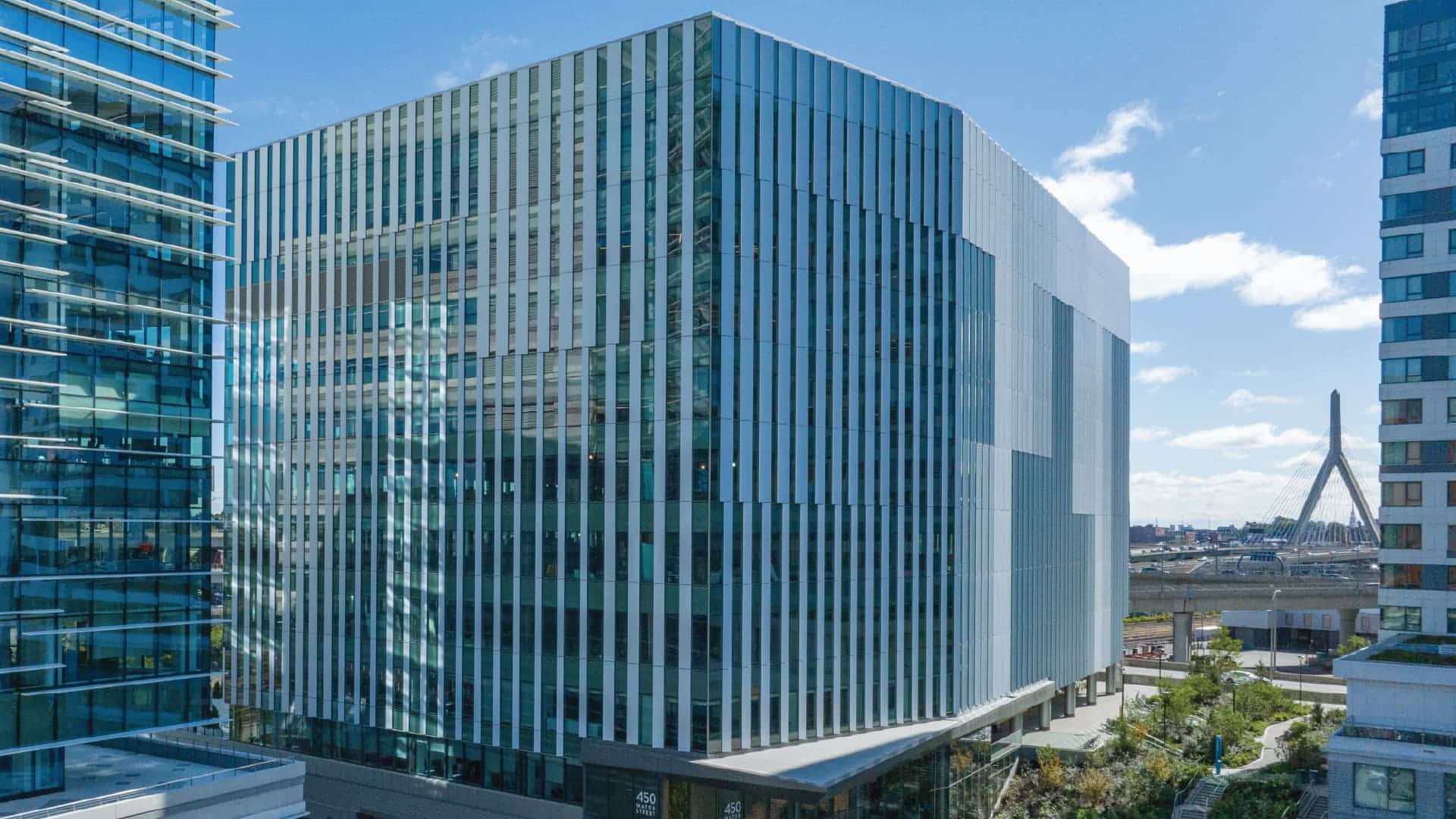 Vertical striped glass building with modern design and Zakim Bridge visible in background skyline