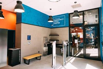 Brightly lit entry to Kendall Square Community Cycle Center featuring turnstiles and blue signage