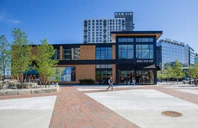 Exterior of REI Co-op retail store with modern facade, large windows, and pedestrians approaching