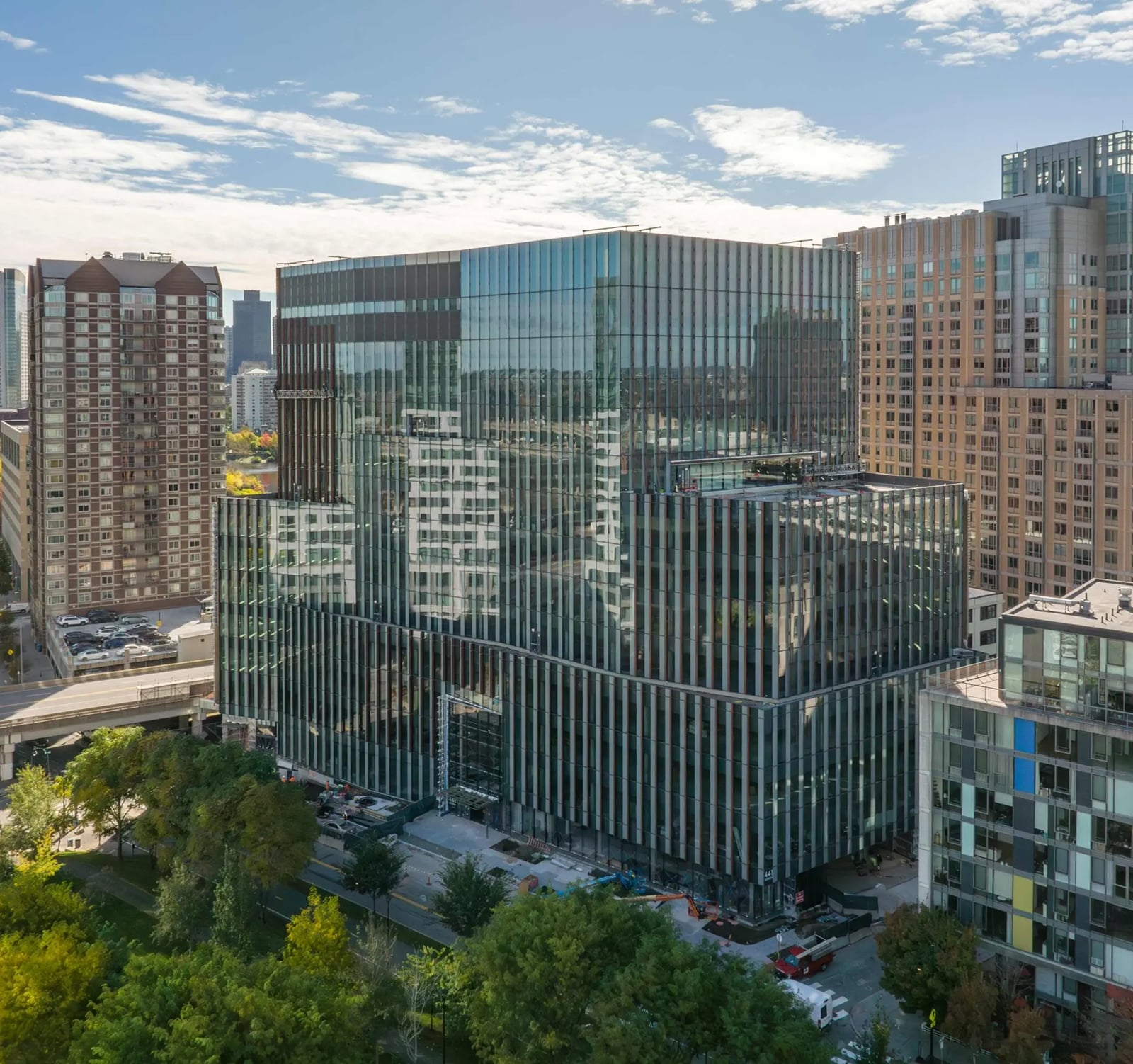 Glass-wrapped high-rise building reflecting surrounding cityscape and blue skies in urban setting
