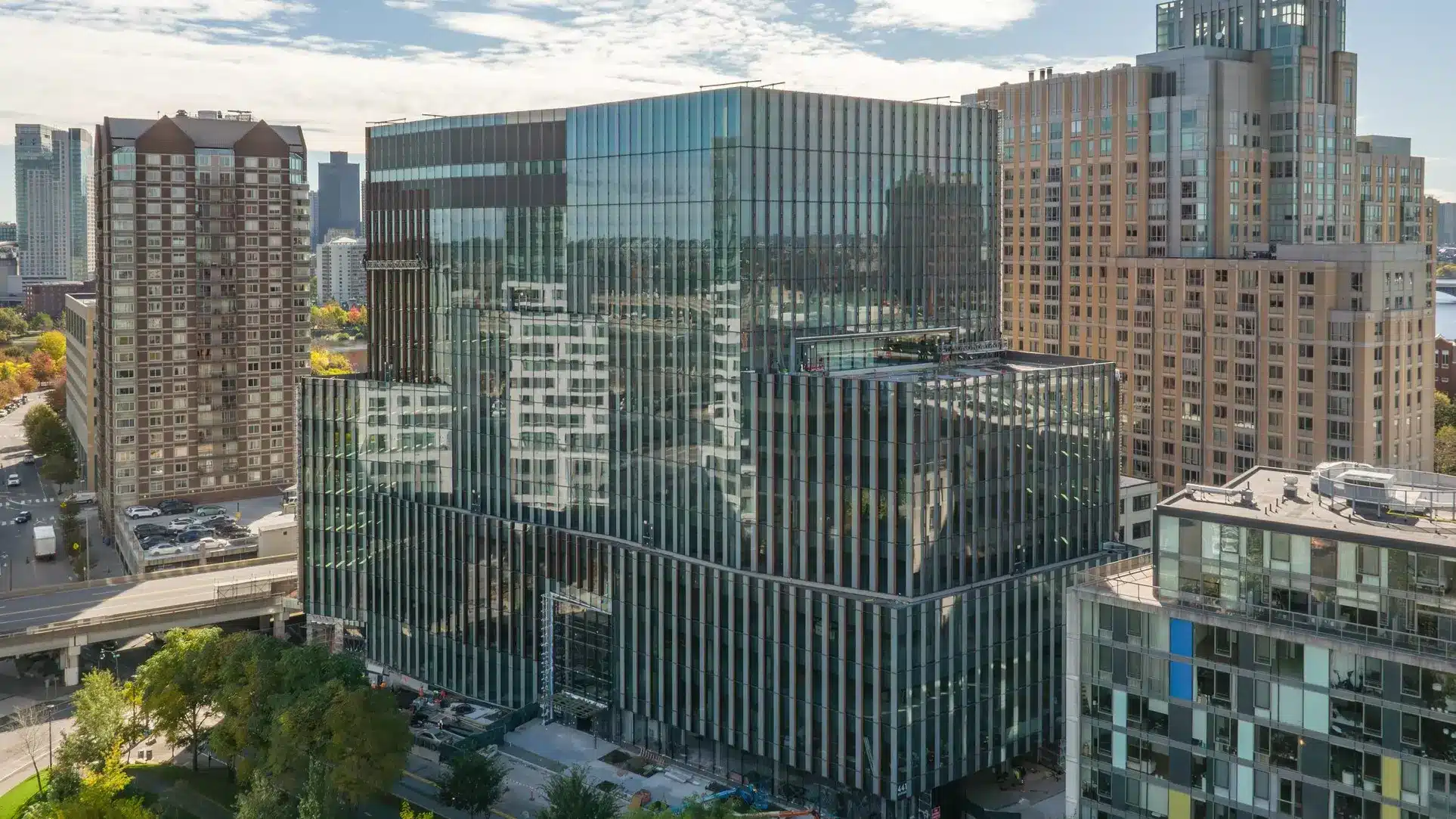 Vertical close-up of glass office tower featuring striped cladding and mirrored building reflections