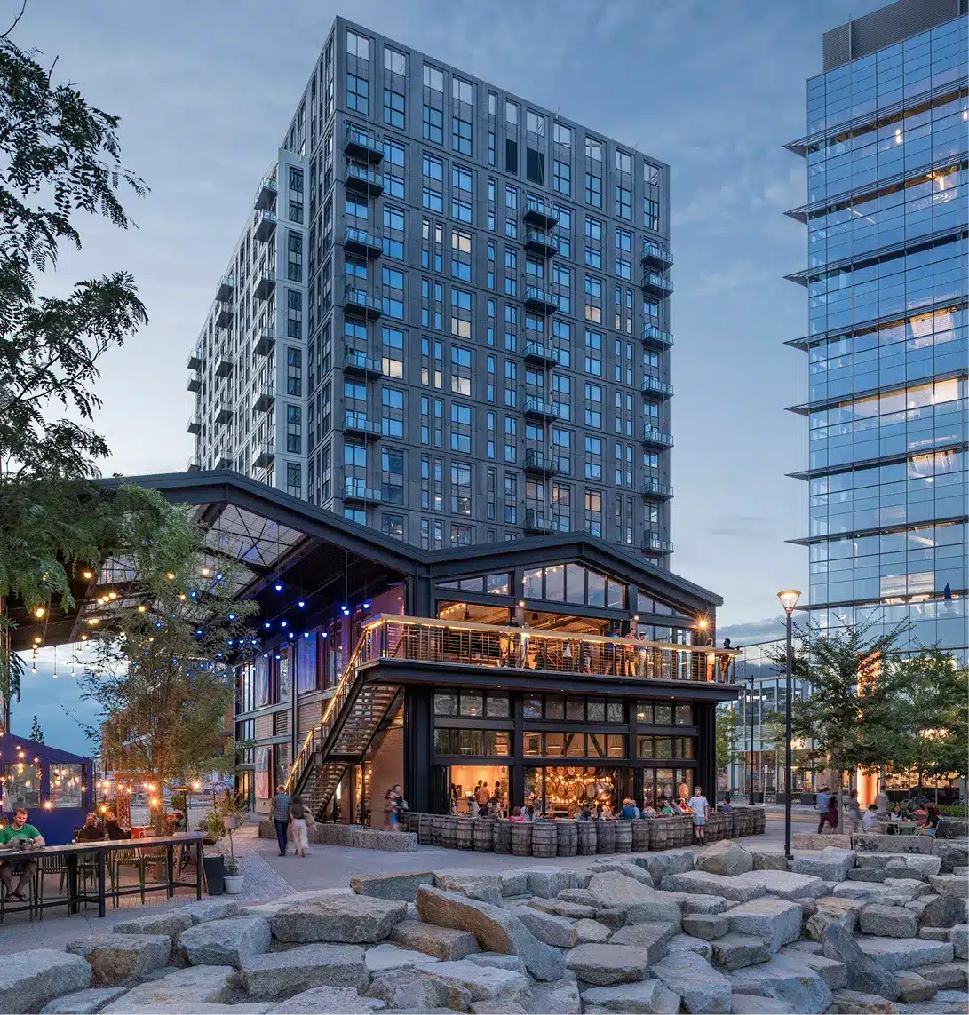 Nighttime scene at bustling restaurant plaza beneath residential towers and twinkling city lights