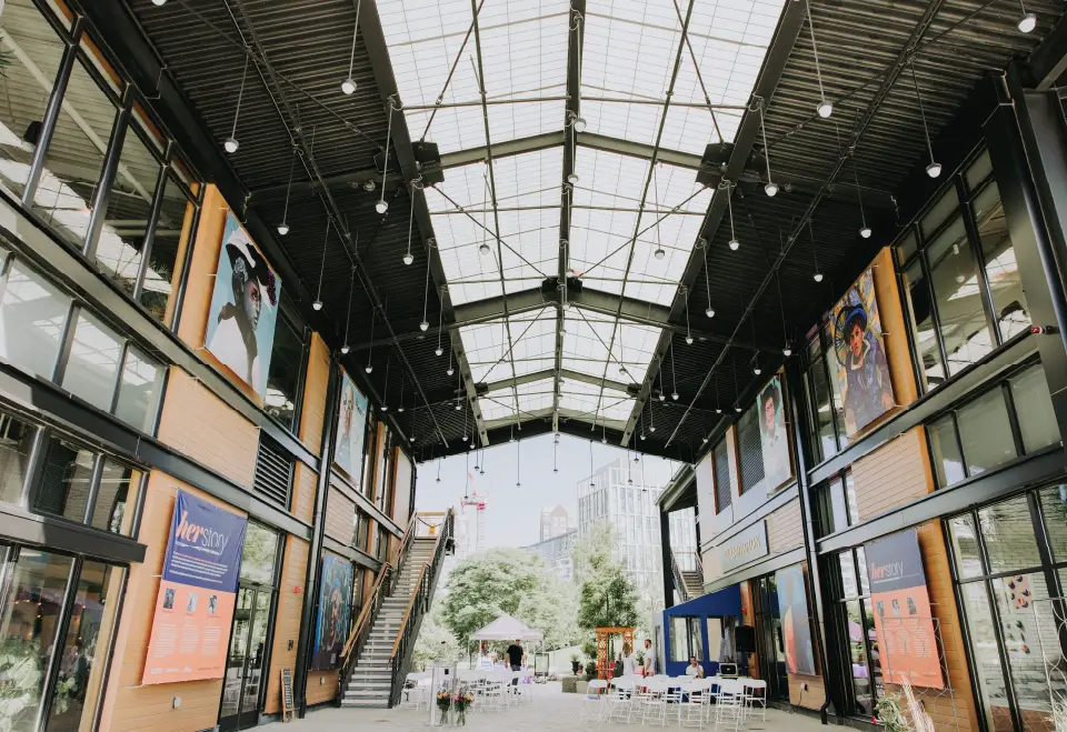 Covered shopping arcade featuring portrait artwork, string lights, and open storefronts