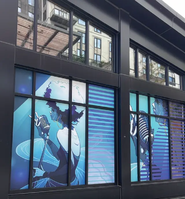 Window art featuring jazz singer in profile, holding microphone against a glowing blue backdrop