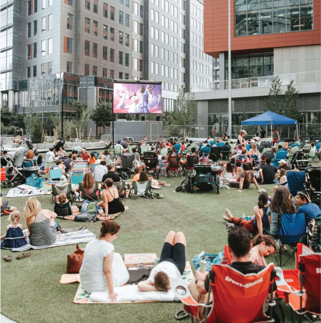 Open green space framed by modern architecture, used for events and recreation in urban plaza