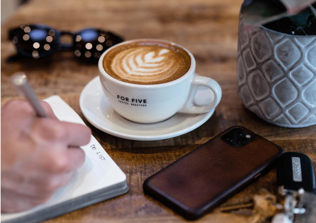 Latte art in white cup from For Five Coffee Roasters on rustic wooden table surface