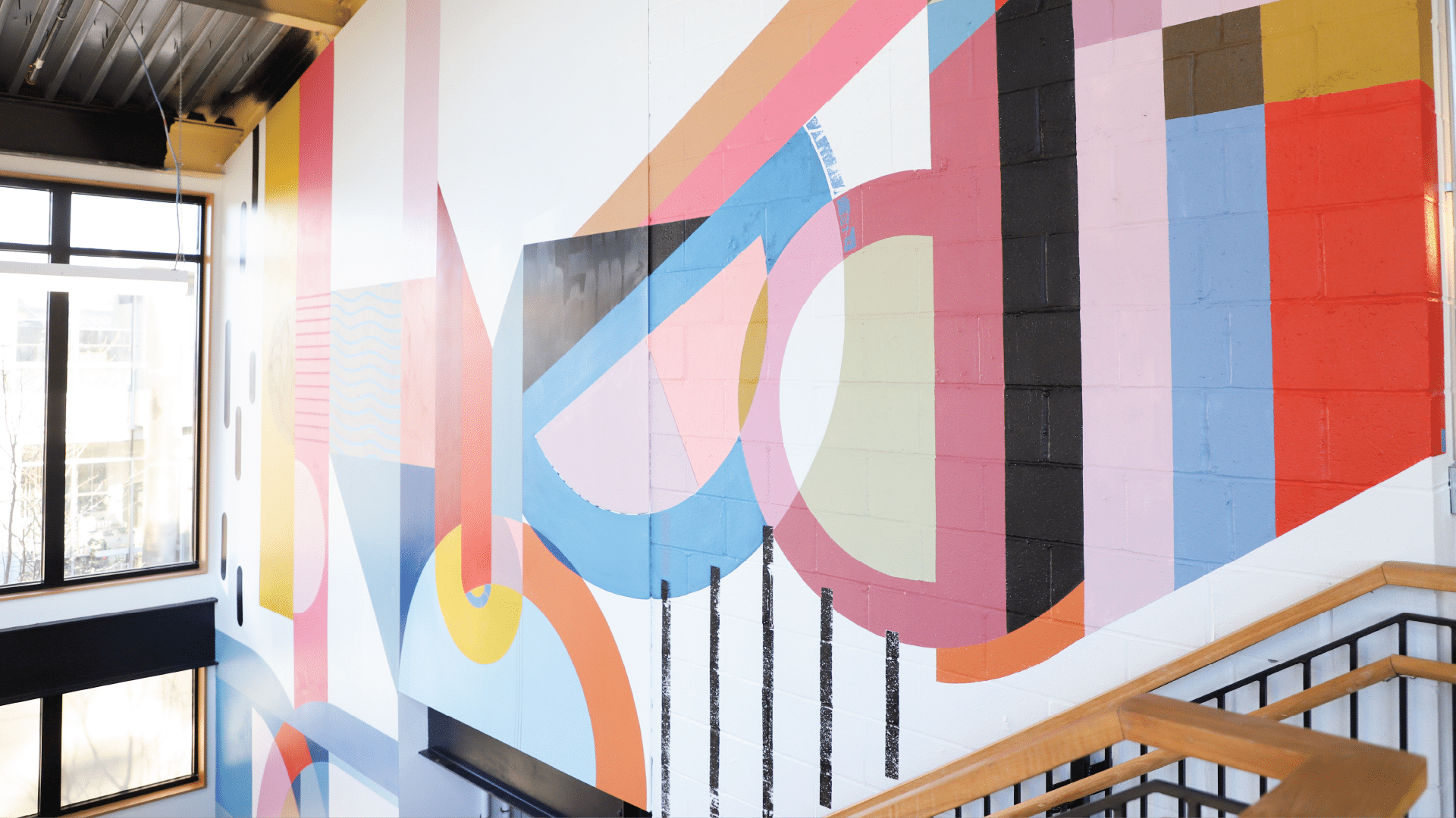 LampLighter Brewery: Abstract mural with bold shapes and lines painted inside bright, industrial stairwell