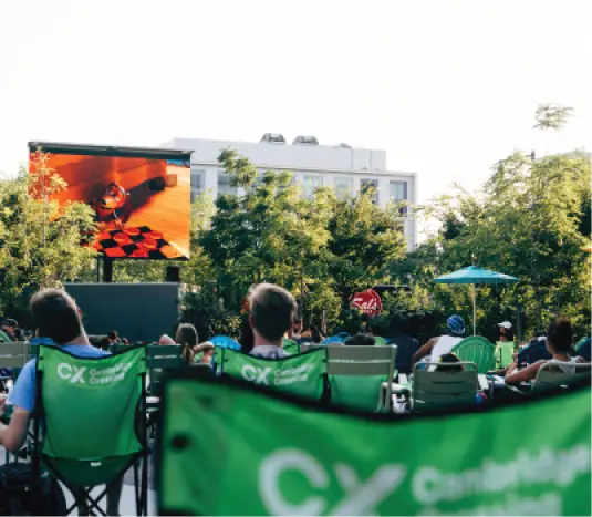 Community gathering watching outdoor movie on big screen with Cambridge Crossing chairs