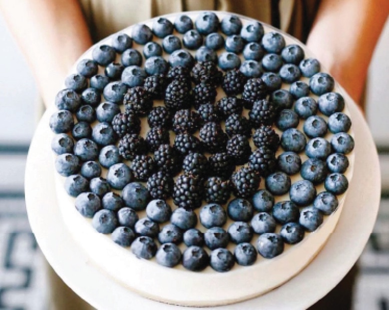Blueberry and blackberry tart beautifully arranged in circular pattern on white ceramic cake stand
