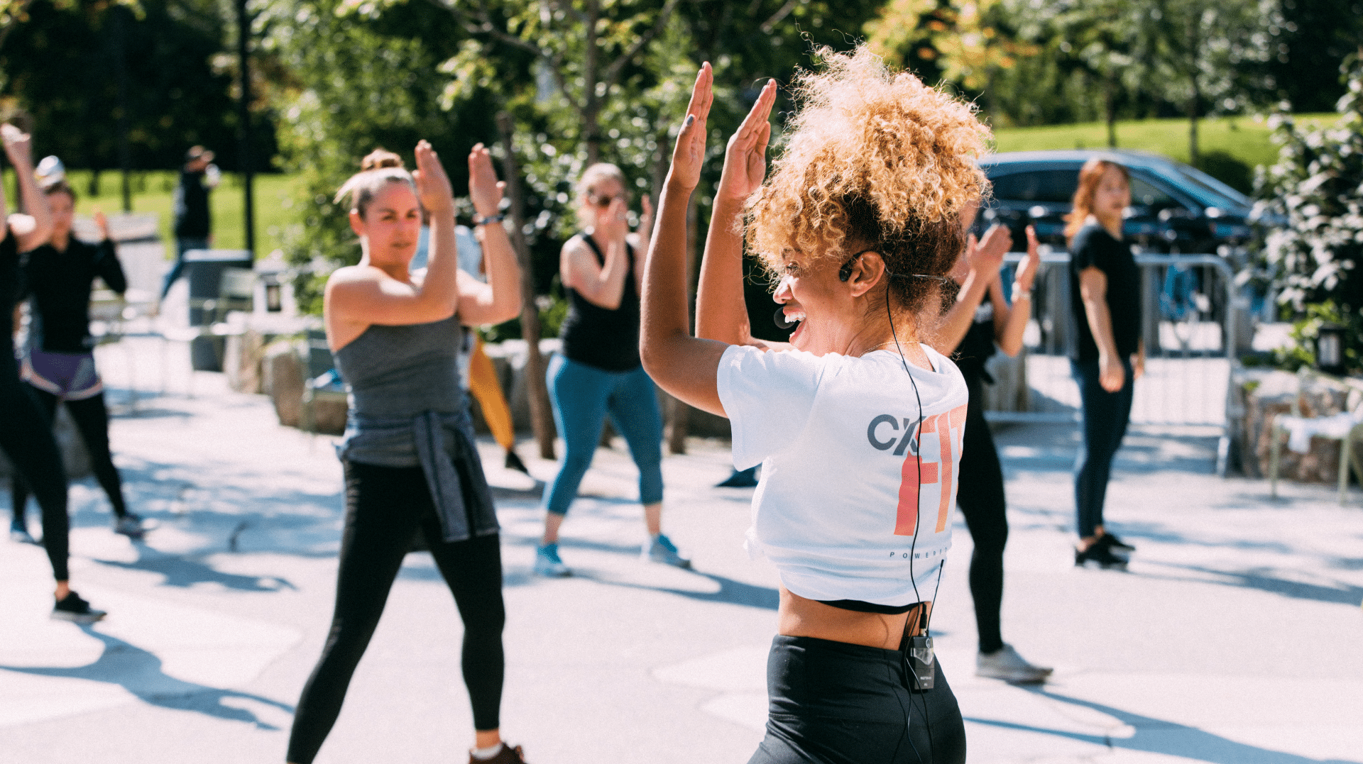 Outdoor fitness class led by energetic instructor in activewear under sunny trees
